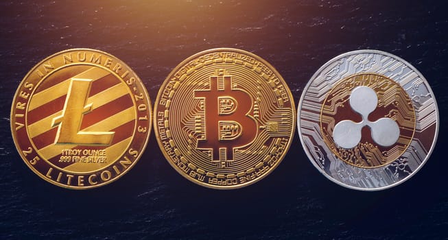 Bitcoin, litecoin and ripple coins currency finance money on graph chart background. Bitcoin as most important cryptocurrency concept. Stack of cryptocurrencies with a golden bitcoin in the middle.