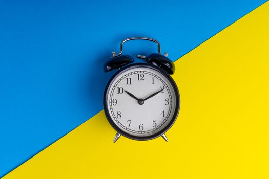 Alarm clock on a blue and yellow background. Business Concept