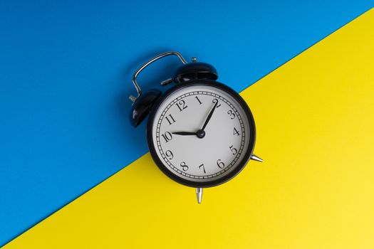 Alarm clock on a blue and yellow background. Business Concept