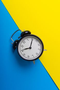 Alarm clock on a blue and yellow background. Business Concept