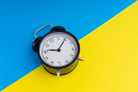 Alarm clock on a blue and yellow background. Business Concept