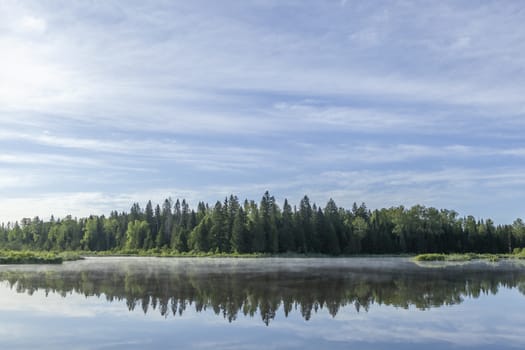 Idyllic landscape. The sky and the forest are reflected in the river.