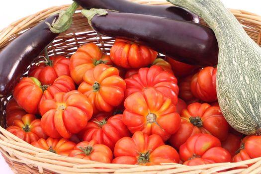 Organic tomatoes, eggplant and pumpkin in wicker basket