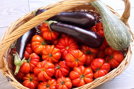 Organic tomatoes, eggplant and pumpkin in wicker basket