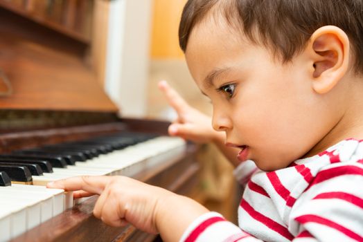 Litlle boy playing the piano, toddler learning music at home