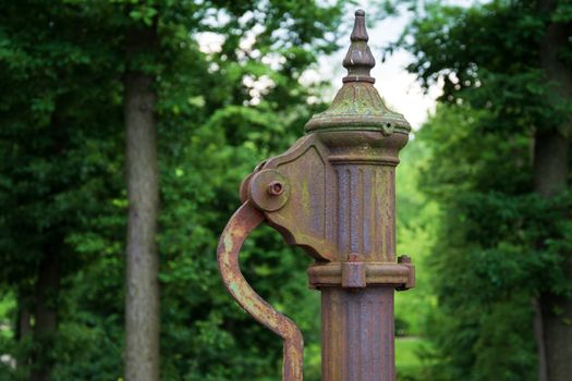 hand water pump. Old Manual pump well in park. Photo of old style well object. Old Antique metal mechanism.