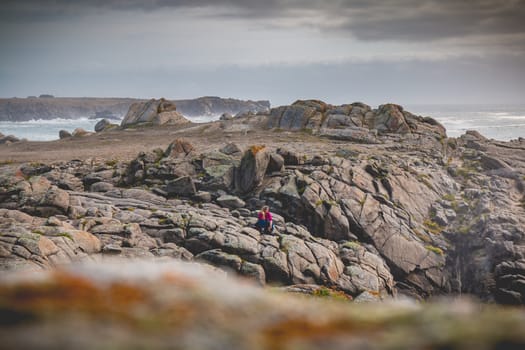 young woman sitting on rocks near the sea of the island of Yeu