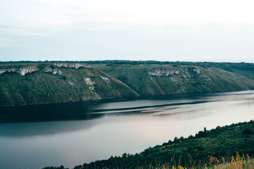 A large river on a background of rocky hills covered with trees.