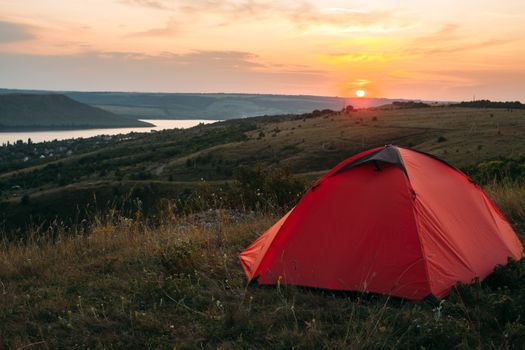 Orange tent at sunset in the mountains. Camping in nature.