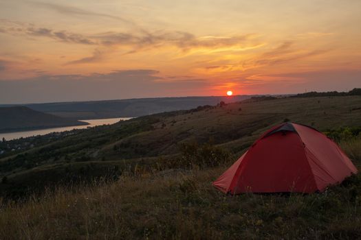 Orange tent at sunset in the mountains. Camping in nature.