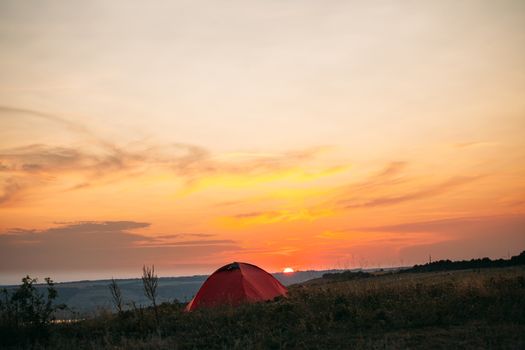 Orange tent at sunset in the mountains. Camping in nature.