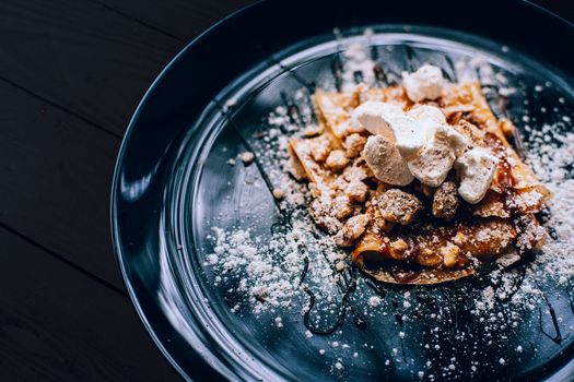 Plate with folded pancake caramel coated walnuts and marshmallows.