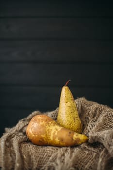 Still life with pears on burlap on a dark wooden photo. Pears Conference