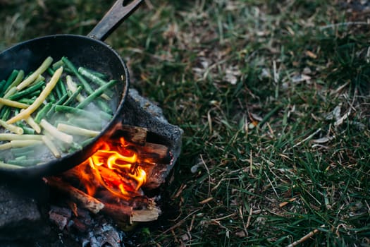 String beans in a pan. Cooking vegetables on an open fire. Food on a camping trip.