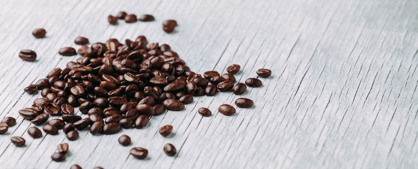 A scattering of coffee beans on a white wooden background. Place under the inscription.