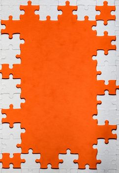 Framing in the form of a rectangle, made of a white jigsaw puzzle. Frame text and jigsaw puzzles. Frame made of jigsaw puzzle pieces on orange background.
