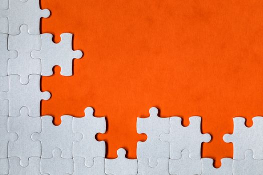 White jigsaw puzzle. White puzzle pieces on color background. Unfinished white jigsaw puzzle pieces on color background. 