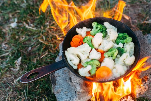 Cauliflower, broccoli and carrot in a pan. Cooking on an open fire. Outdoor food. Grilled vegetables.