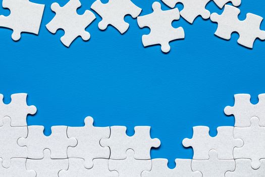White jigsaw puzzle. White puzzle pieces on color background. Unfinished white jigsaw puzzle pieces on color background. 