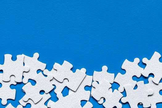 White jigsaw puzzle. White puzzle pieces on color background. Unfinished white jigsaw puzzle pieces on color background. 