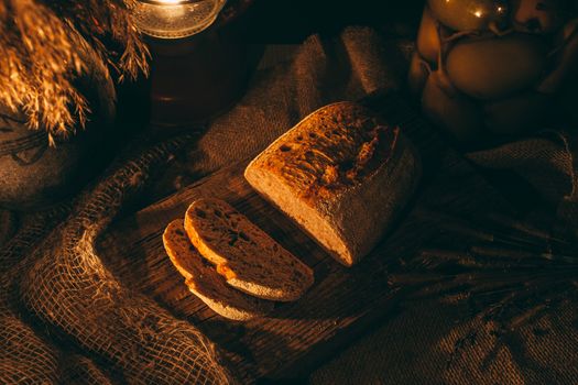 Sliced ​​bread with jam in the light of candles on a wooden board. Rustic atmosphere.Photo from the top