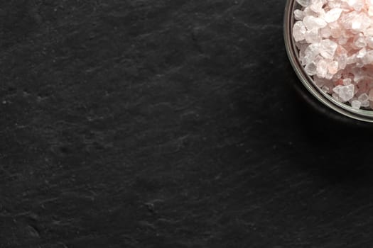 Spilled salt near a saucer full of salt on a black slate board