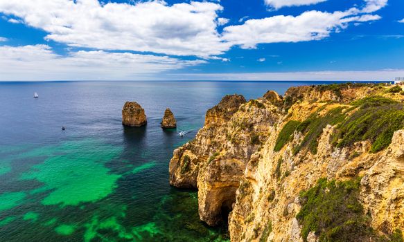 Panoramic view, Ponta da Piedade near Lagos in Algarve, Portugal. Cliff rocks and tourist boat on sea at Ponta da Piedade, Algarve region, Portugal. Ponta da Piedade, Algarve region, Portugal.