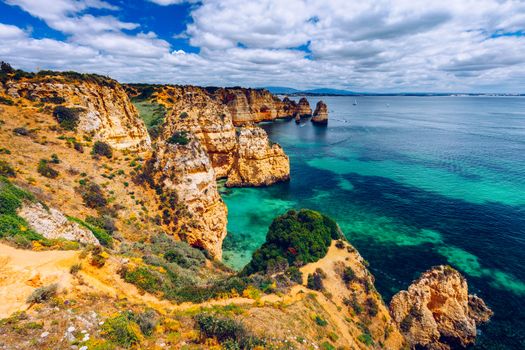 Panoramic view, Ponta da Piedade near Lagos in Algarve, Portugal. Cliff rocks and tourist boat on sea at Ponta da Piedade, Algarve region, Portugal. Ponta da Piedade, Algarve region, Portugal.