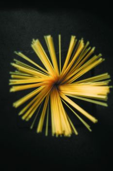 Unfolded spaghetti in a jar on a black wooden background