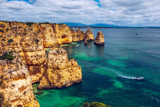 Panoramic view, Ponta da Piedade near Lagos in Algarve, Portugal. Cliff rocks and tourist boat on sea at Ponta da Piedade, Algarve region, Portugal. Ponta da Piedade, Algarve region, Portugal.