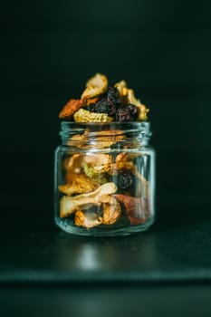 Dried fruits on a black background in a transparent jar