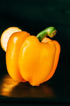 Yellow bell pepper with water droplets on a black background