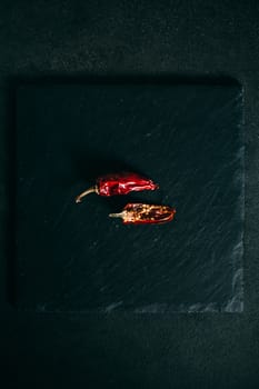 Hot dry red chili peppers on a slate plate on a black background