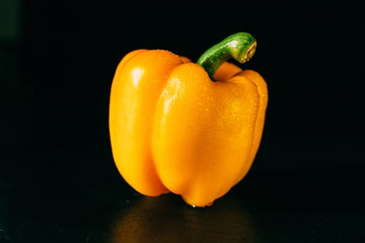 Yellow bell pepper with water droplets on a black background