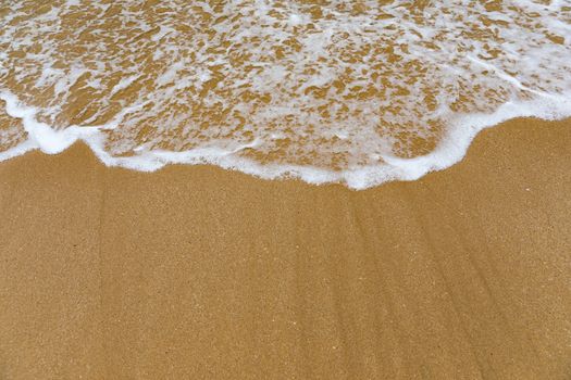Blue ocean wave on sandy beach. Soft wave of blue ocean on sandy beach. Background. Top view of Beautiful beach with tranquil wave, sea and ocean background, summer vacation concept. 
