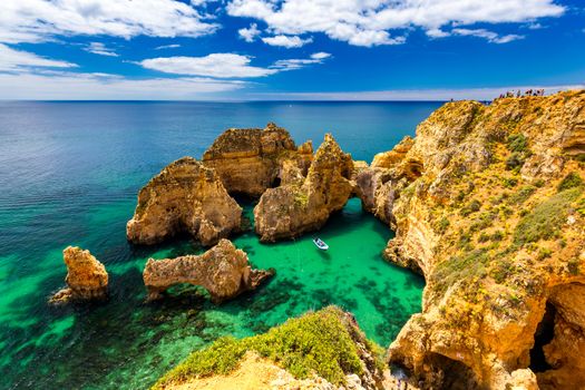 Panoramic view, Ponta da Piedade near Lagos in Algarve, Portugal. Cliff rocks and tourist boat on sea at Ponta da Piedade, Algarve region, Portugal. Ponta da Piedade, Algarve region, Portugal.