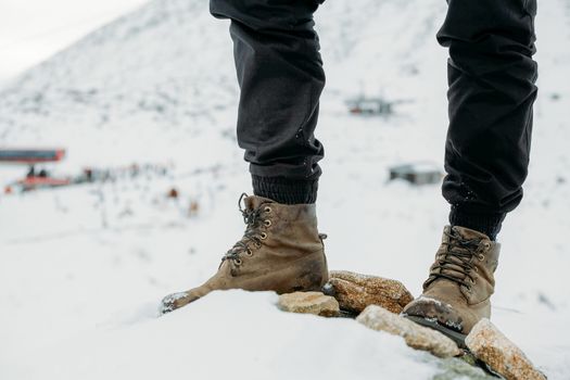 Feet in boots on a background of snowy mountains after a long walk
