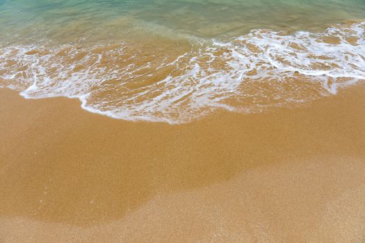 Blue ocean wave on sandy beach. Soft wave of blue ocean on sandy beach. Background. Top view of Beautiful beach with tranquil wave, sea and ocean background, summer vacation concept. 