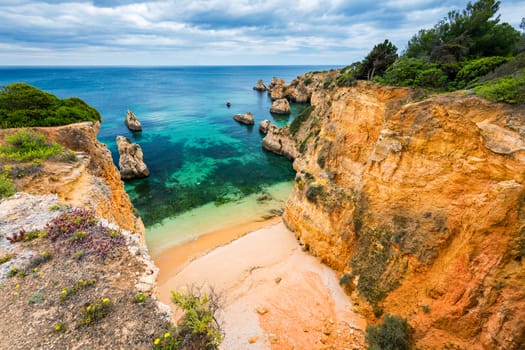 View of stunning beach with golden color rocks in Alvor town , Algarve, Portugal. View of cliff rocks on Alvor beach, Algarve region, Portugal.