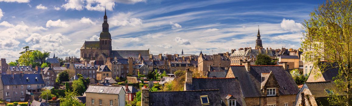 Beautiful view of scenic narrow alley with historic traditional houses and cobbled street in an old town of Dinan with blue sky and clouds. Brittany (Bretagne), France