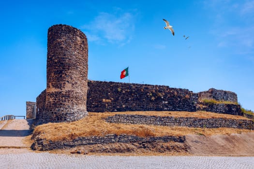 Ruins of Castle in Aljezur with waving portuguese flag, Algarve, Portugal. Aljezur castle, Portugal Arabian gorgeous castle, made of stone with a tower. Aljezur, Algarve, Portugal.