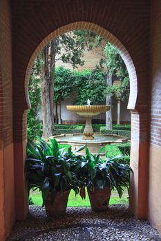 Nice arch door and fountain in ancient Arabian palace Alhambra. Granada, Spain.