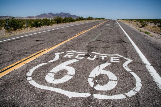 Long US road with a Route 66 sign painted on it