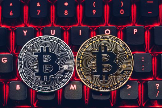 Bitcoin on compuer keyboard in background, symbol of electronic virtual money and mining cryptocurrency concept. Coin crypto currency bitcoin lies on the keyboard. Bitcoin on keyboard.