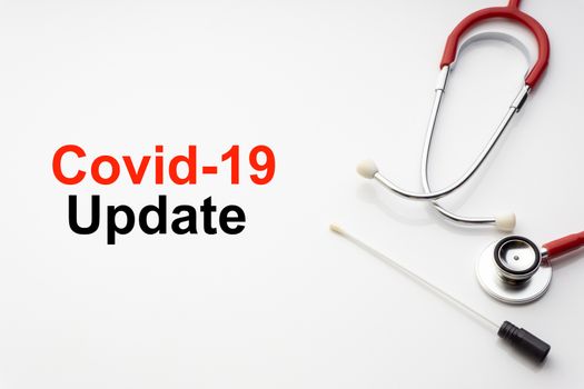 COVID-19 UPDATE text with stethoscope and medical swab on white background. Covid or Coronavirus Concept 