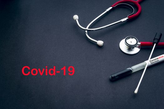 COVID-19 text with stethoscope and medical swabs on black background. Covid -19 or Coronavirus Concept 