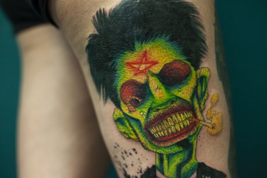 Coloured Tattoo with green face painted in a leg