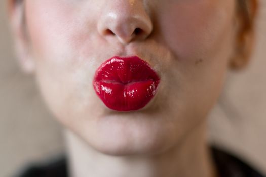 Extreme close up of the face of a woman with bright red lipstick on her lips.