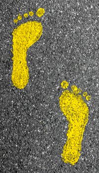 Footprints yellow feet, on a rough asphalt.