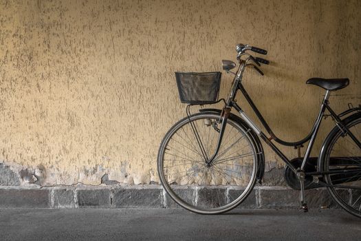 A black bicycle leaning against a wall in the city.